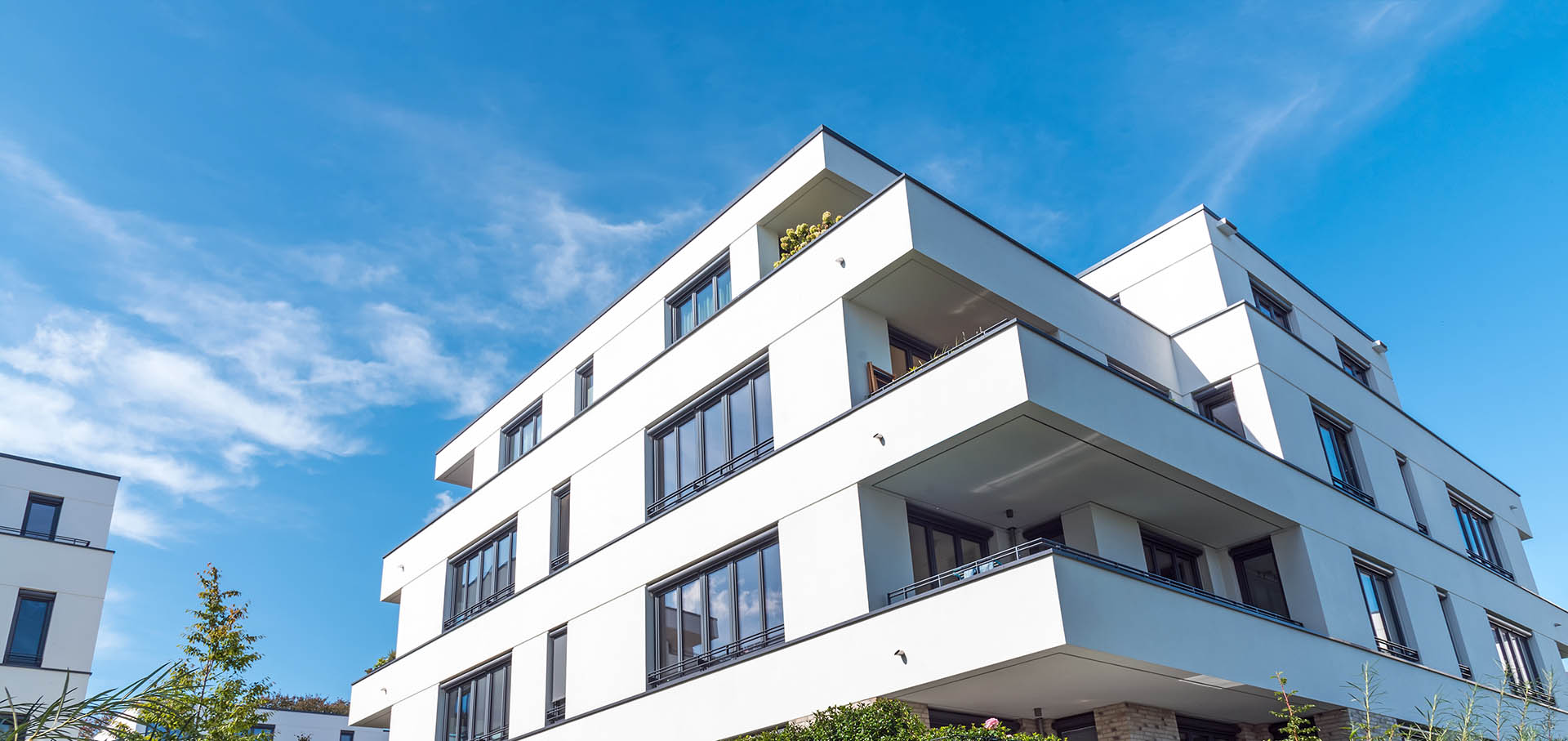 Bright white residential building standing against a blue sky.